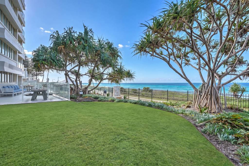Grassed grounds with spreading trees overlooking ocean